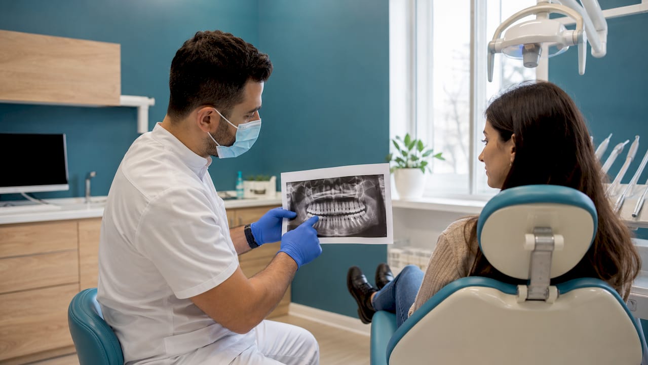 Il dentista illustra al paziente i risultati della radiografia, spiegando con chiarezza ogni dettaglio.