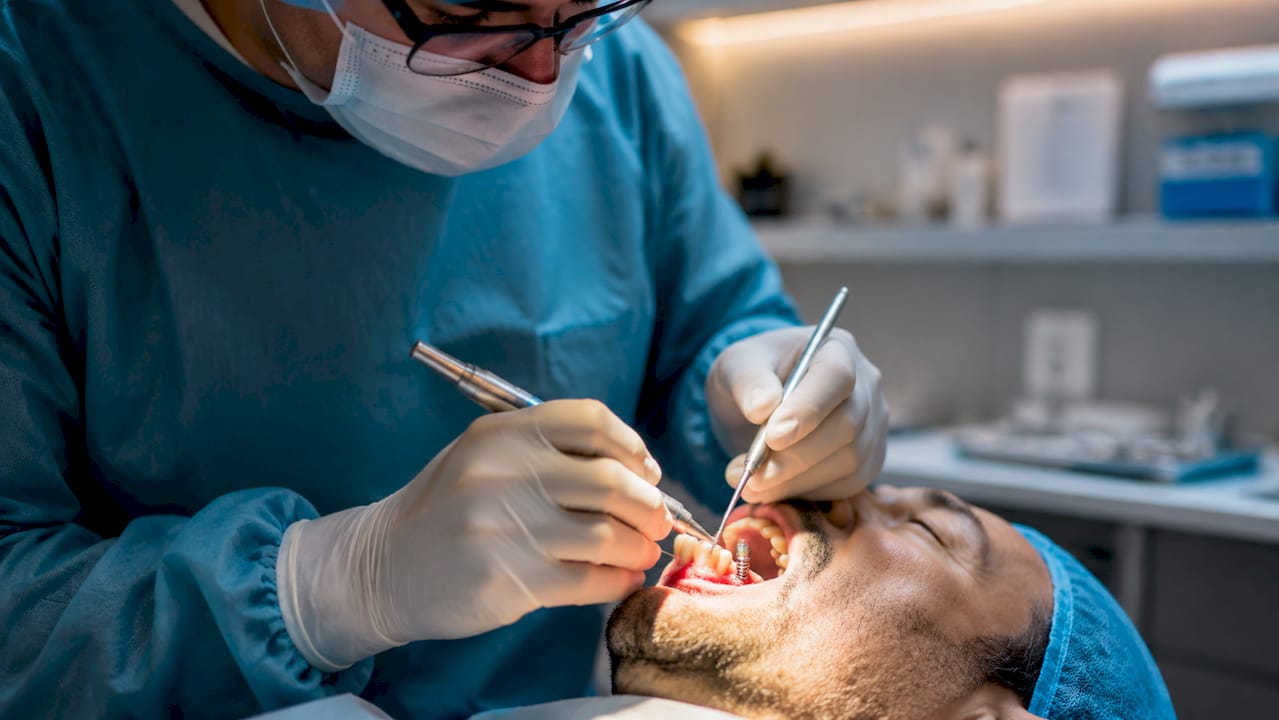 Il dentista posiziona un impianto dentale nella bocca del paziente.