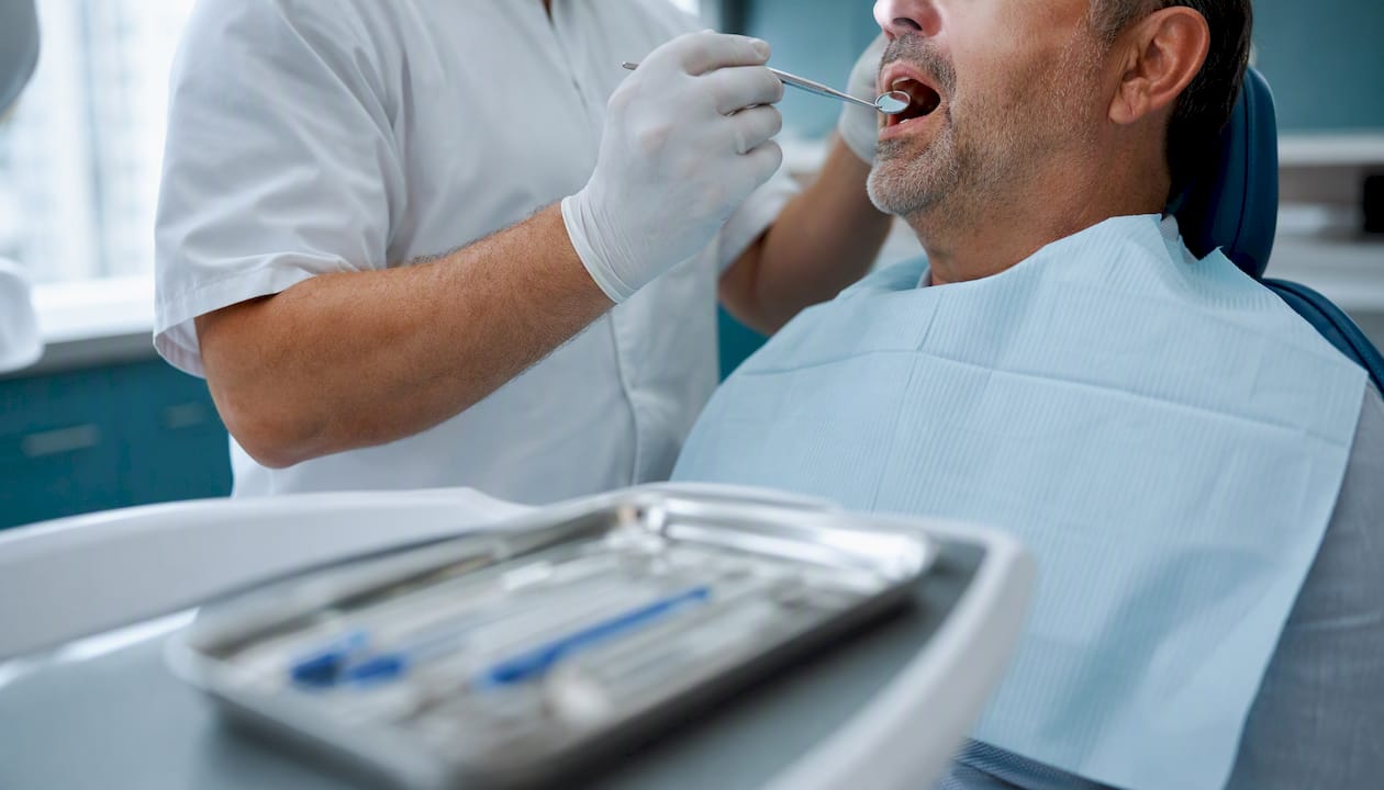 Il dentista controlla attentamente la zona dell’impianto dentale durante la visita.