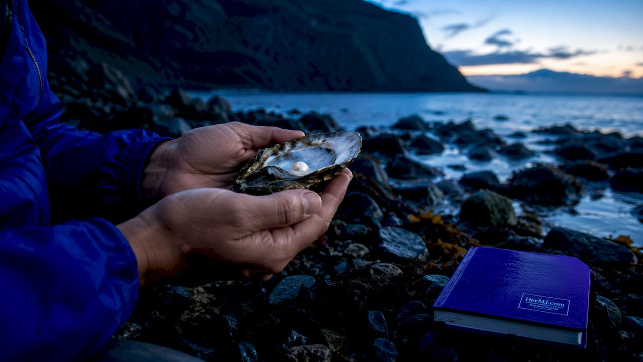 Why Pearl Gifts Symbolize Love: Meaning and History Hands holding oyster with pearl at sunrise by dock