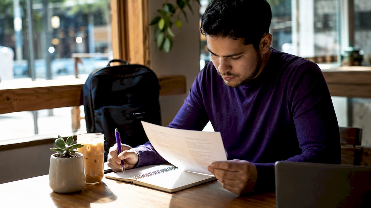 Over-shoulder view of person using laptop and phone