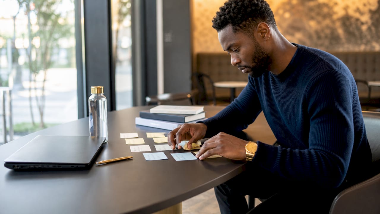 Man organizing work-life balance habit notes at desk