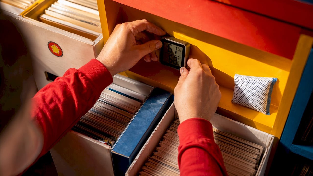 Hands adjusting thermometer in comic storage closet