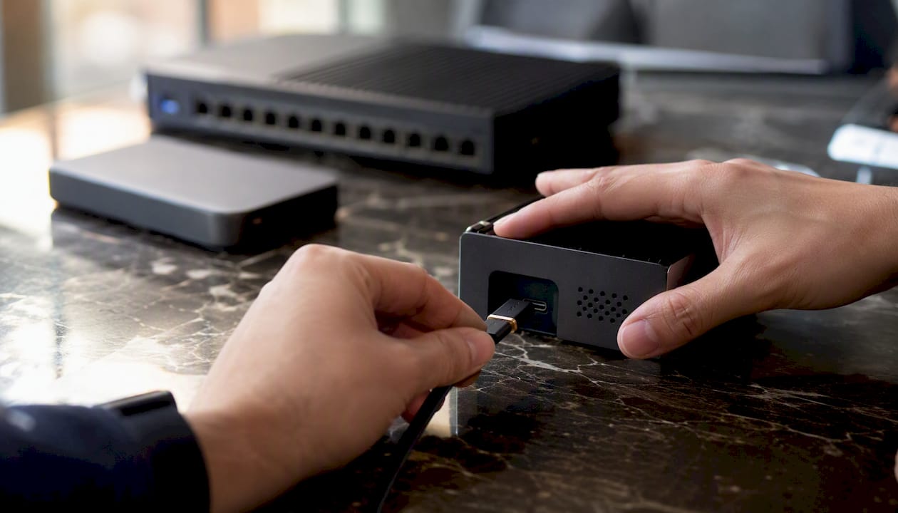Manos conectando un cable al dispositivo para preparar la configuración del POC