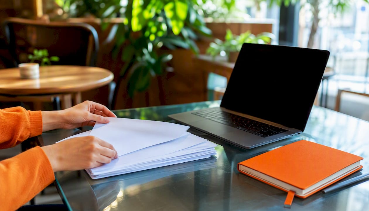 Hands organizing CV files on office desk