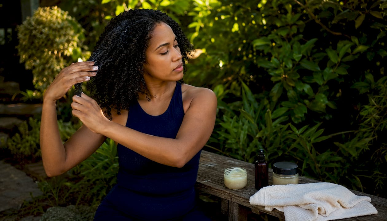 Hands holding plant-based leave-in treatment for curls