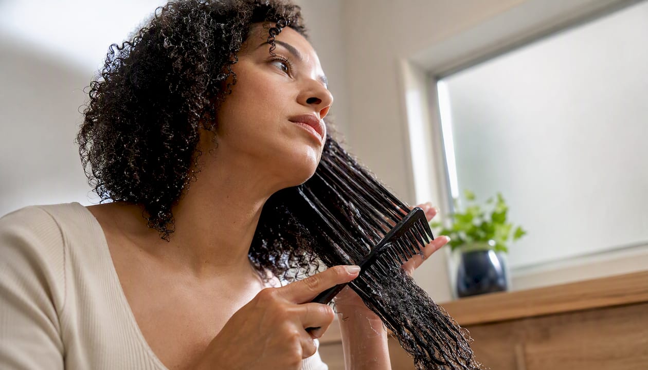 Woman detangling natural hair with conditioner