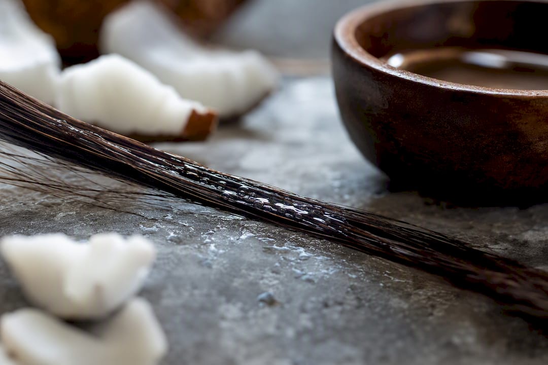 Hair strand coated with coconut oil droplets