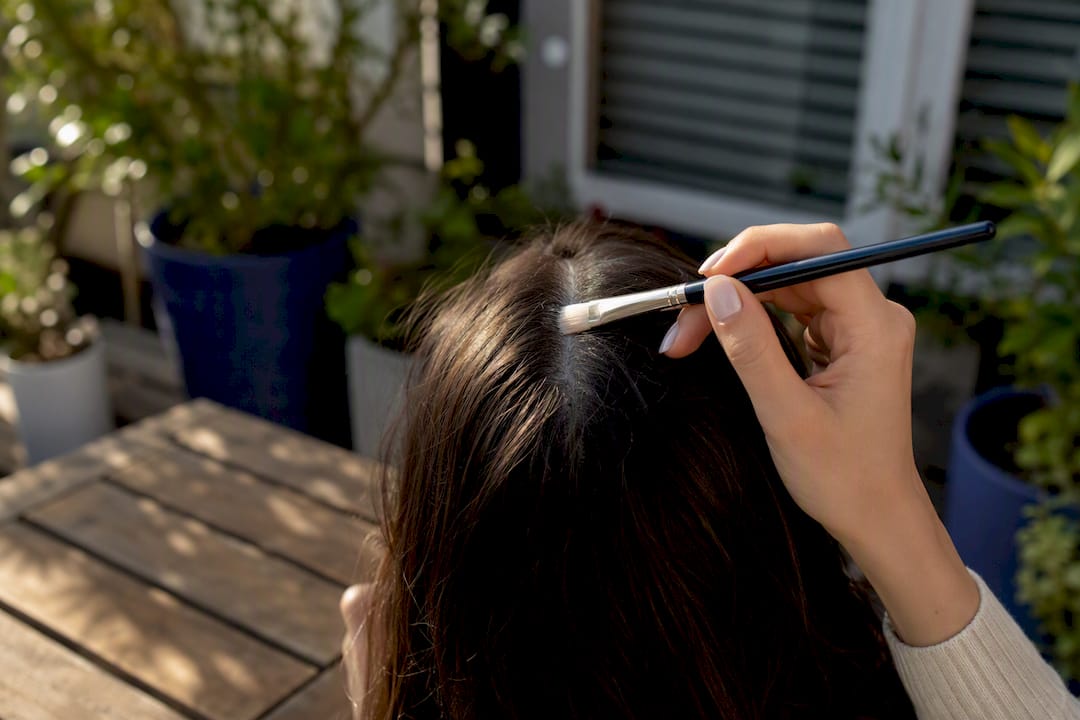 Hand applying scalp SPF with makeup brush