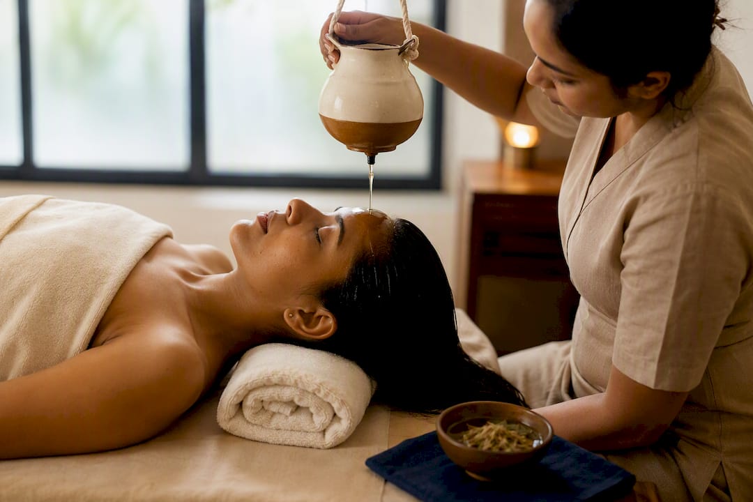 Practitioner performing Shirodhara oil therapy