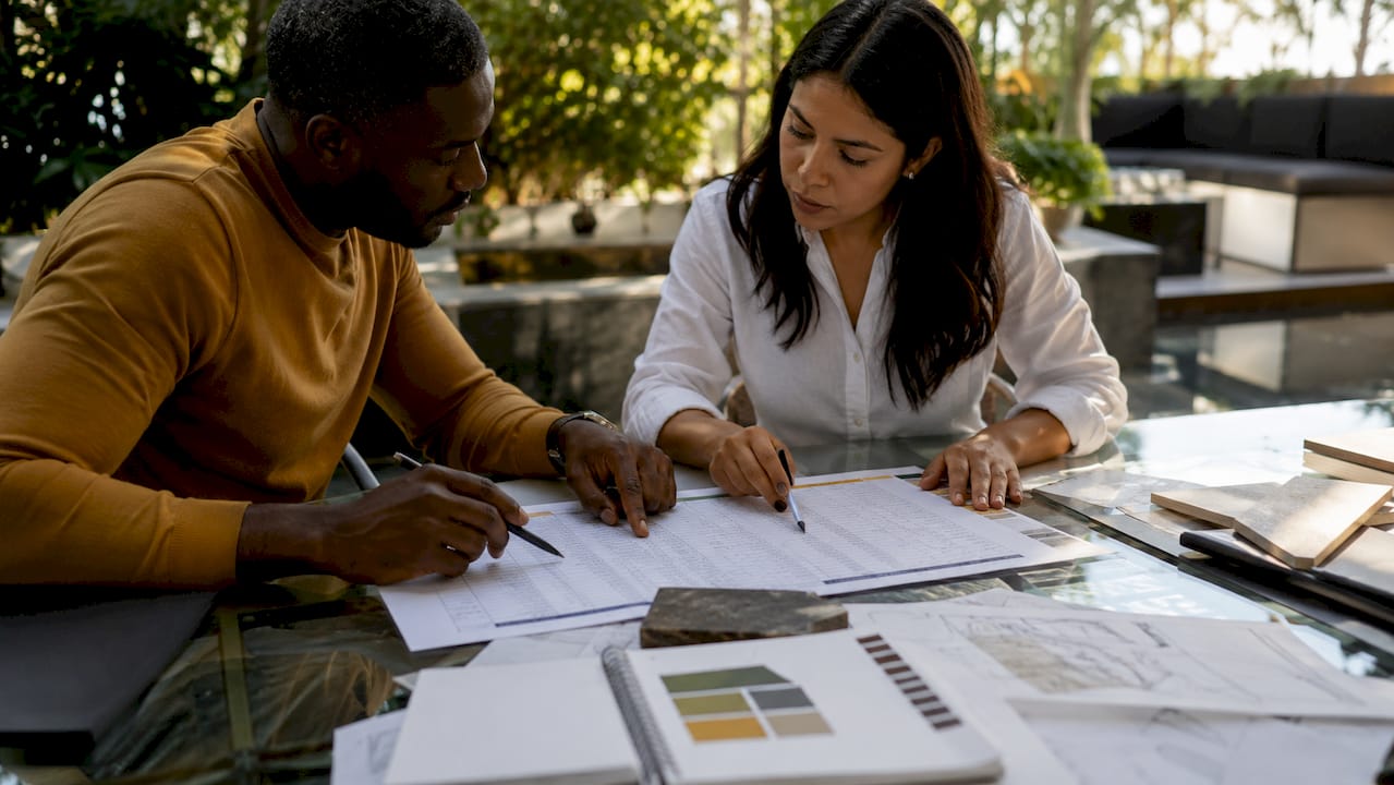 Hands comparing contractor bids spreadsheet