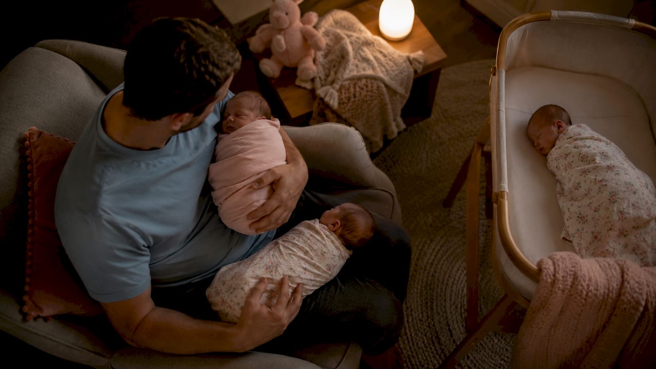 Father soothing newborn twin during night shift