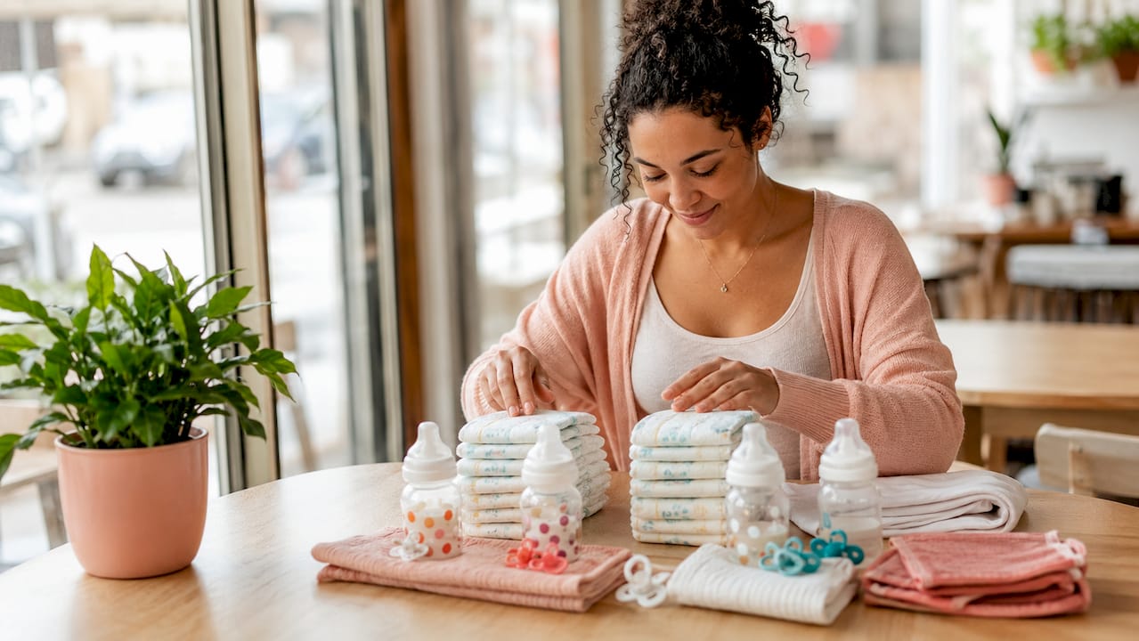 Hands organizing twin baby diapers and bottles