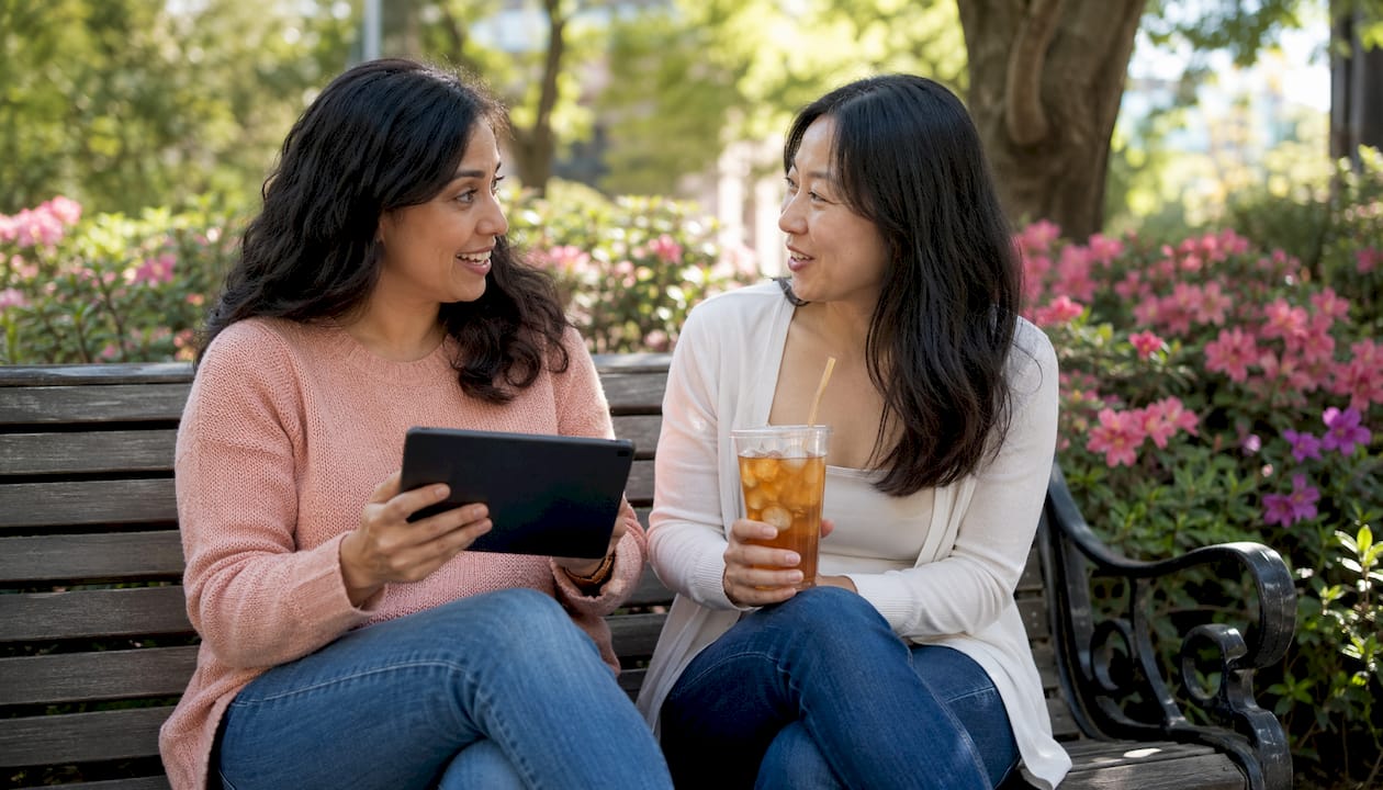Two mothers discussing motherhood app at café table
