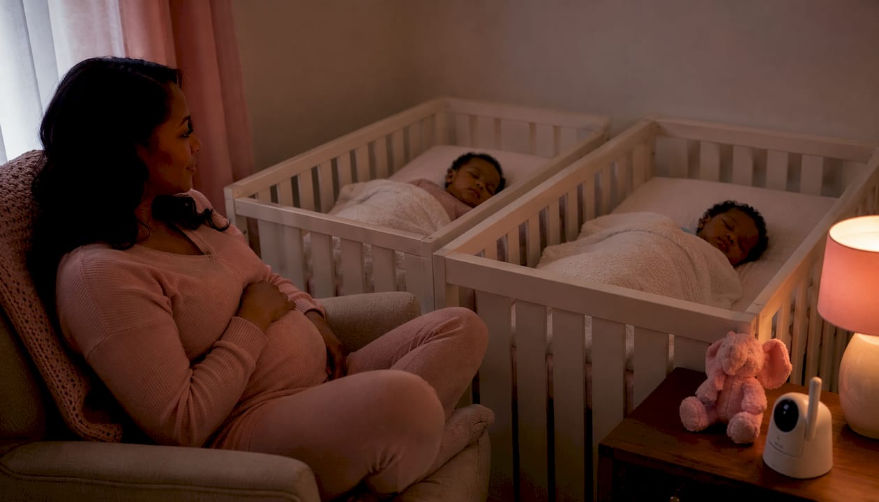 Mother watching sleeping twins in shared nursery