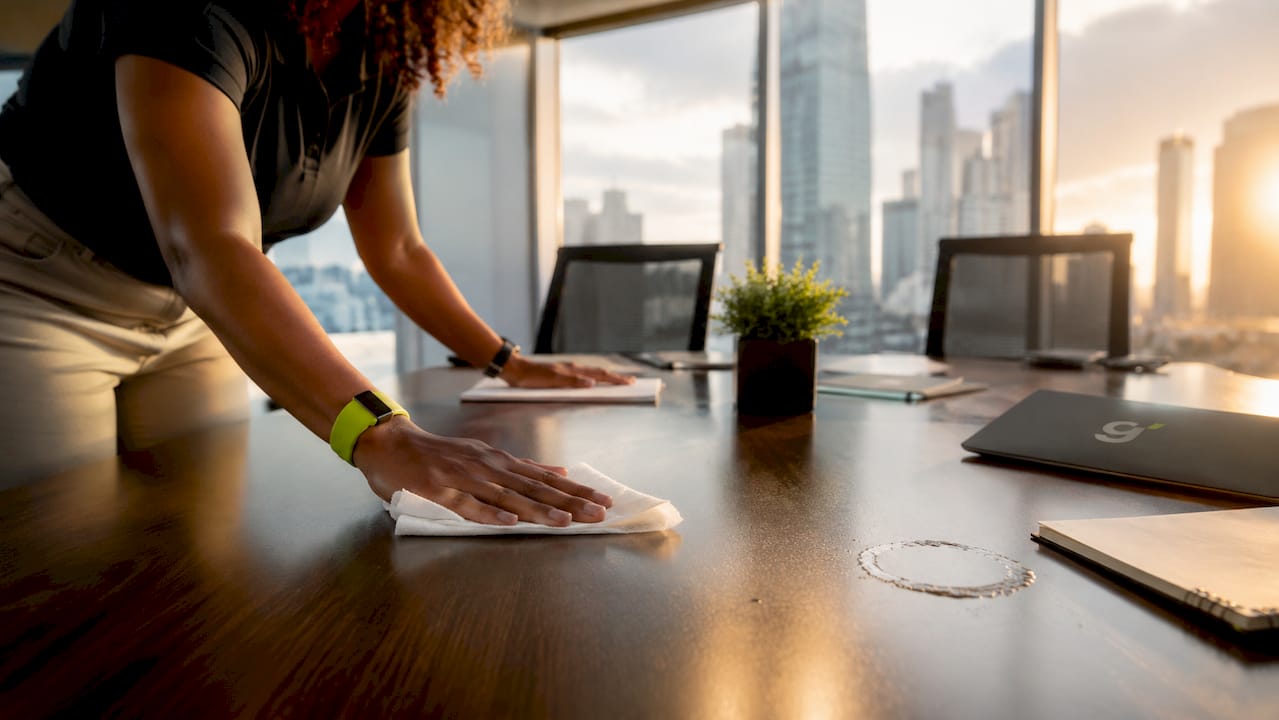 Hands disinfecting office phone in meeting room