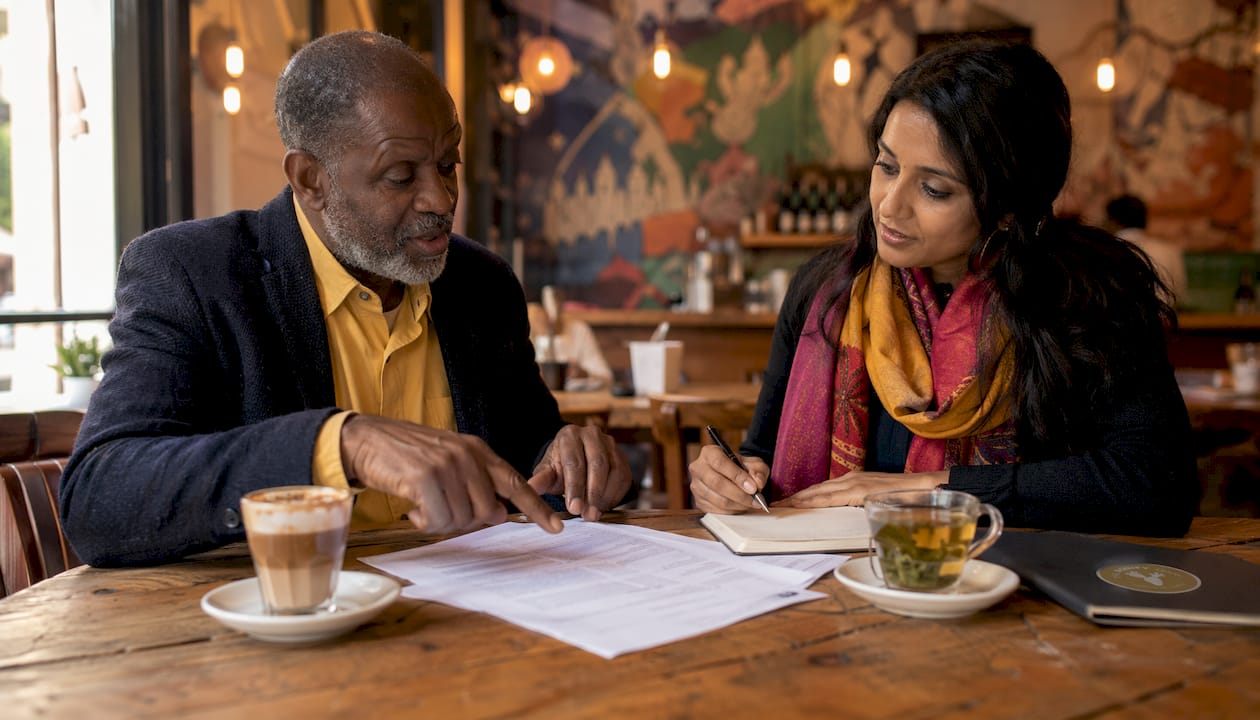 Buyer and seller negotiating real estate contract at café