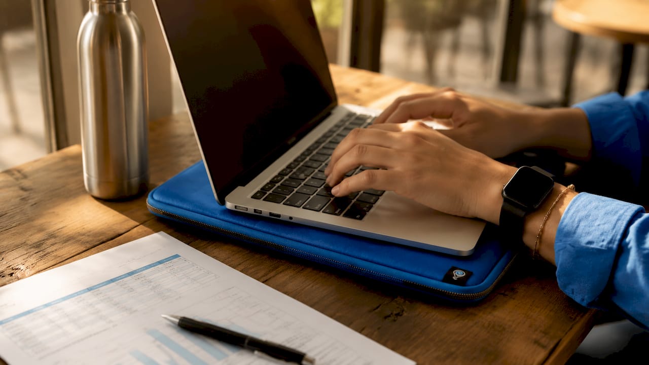 Close-up of hands typing on laptop near hiring metrics spreadsheet