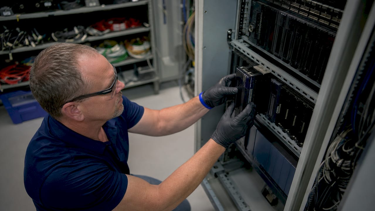 Hands installing GE Series 90-30 I/O module in RX3i rack