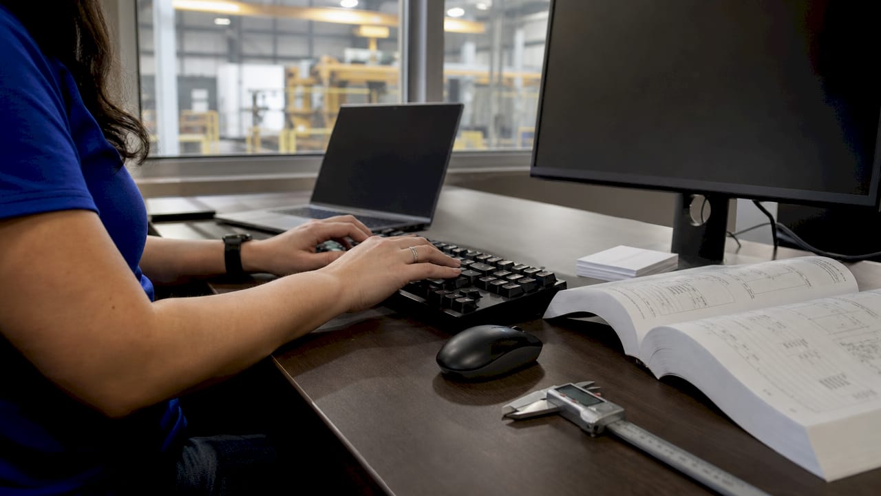 Engineer’s hands typing and referencing manuals