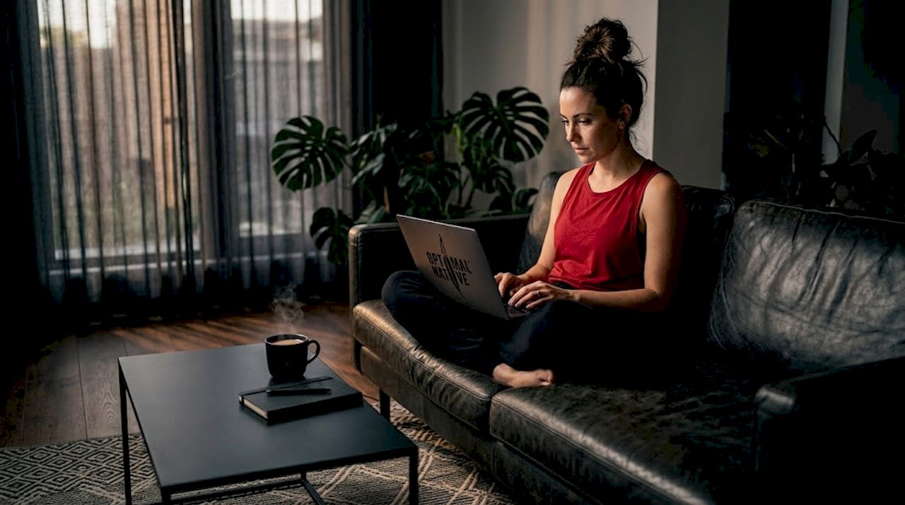 Woman typing on sofa with tea and to-do list
