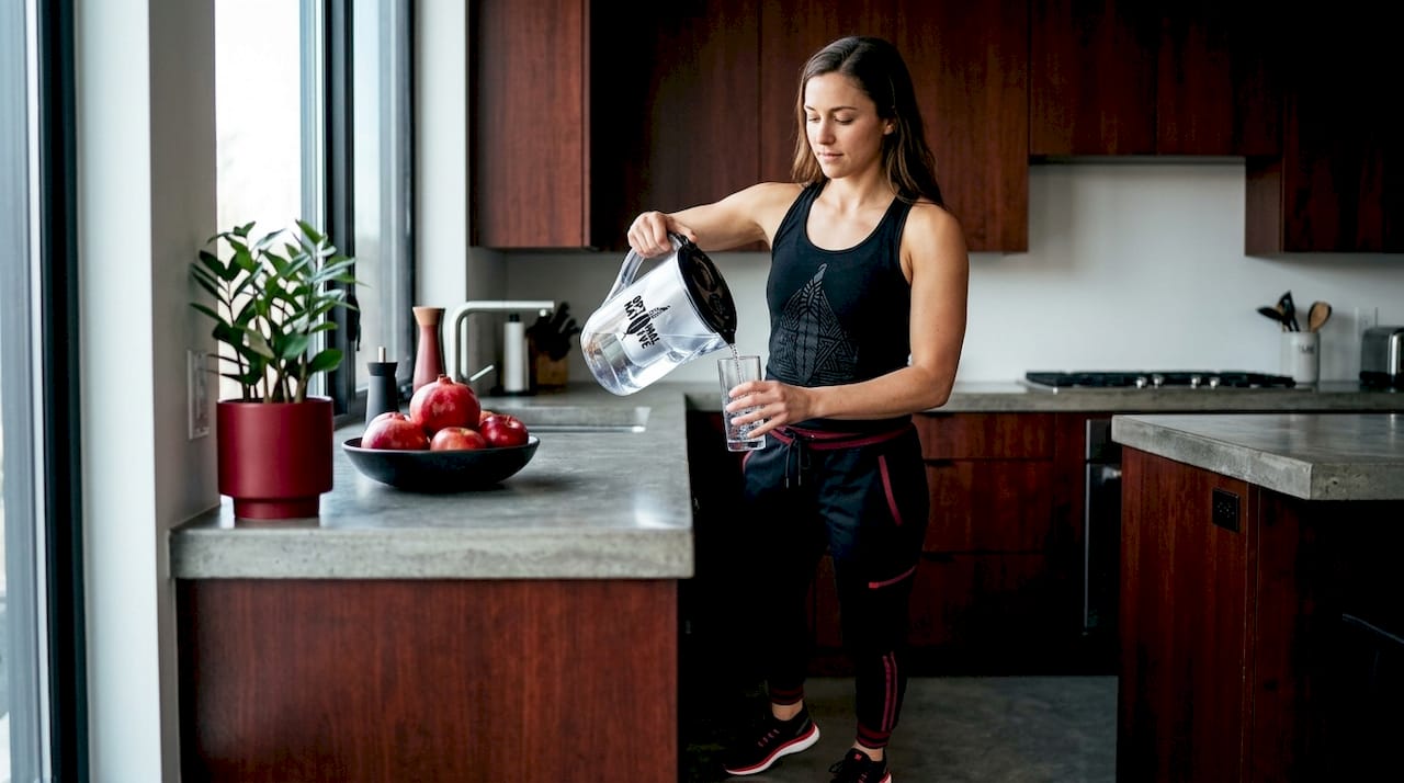 Woman hydrating in kitchen after waking
