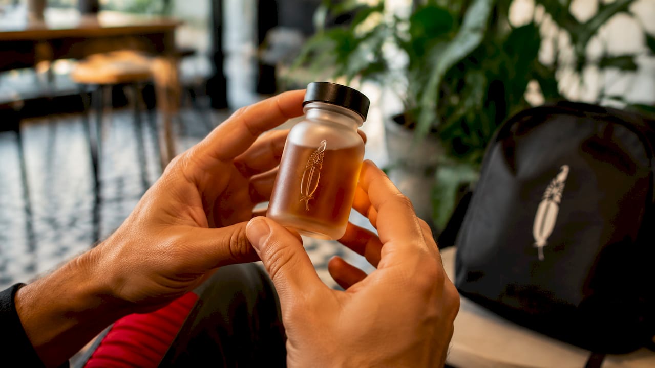 Hands holding GABA supplement vial in kitchen