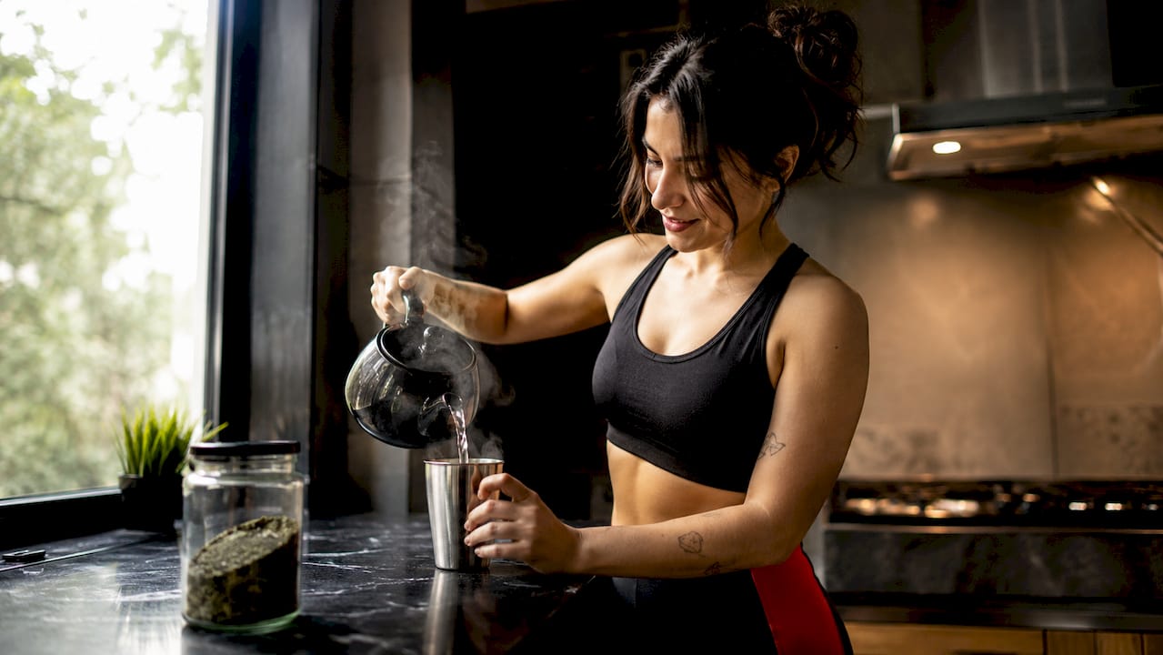 Unas manos sirviendo té verde y preparando yerba mate