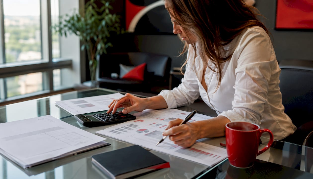 Hands calculating and annotating ad revenue reports