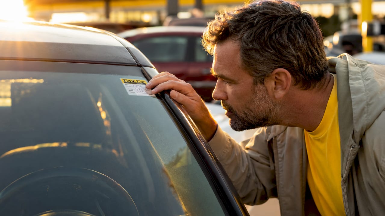 Man checking oil change sticker inside car