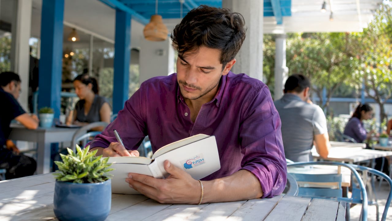 Hombre absorto escribiendo apuntes en una cafetería