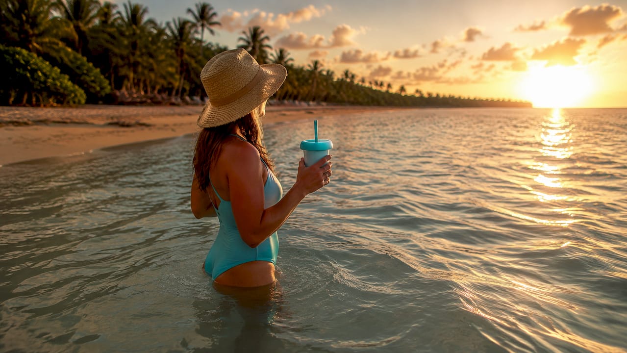 Woman waist-deep in clear water with floating bag