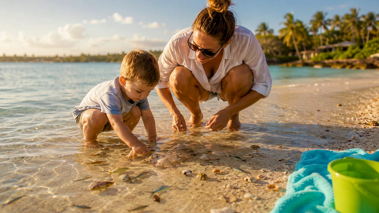 Child picking shells wading in sandbar water