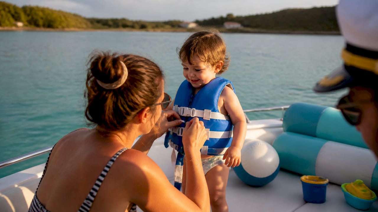 Parent putting life jacket on toddler on calm boat tour
