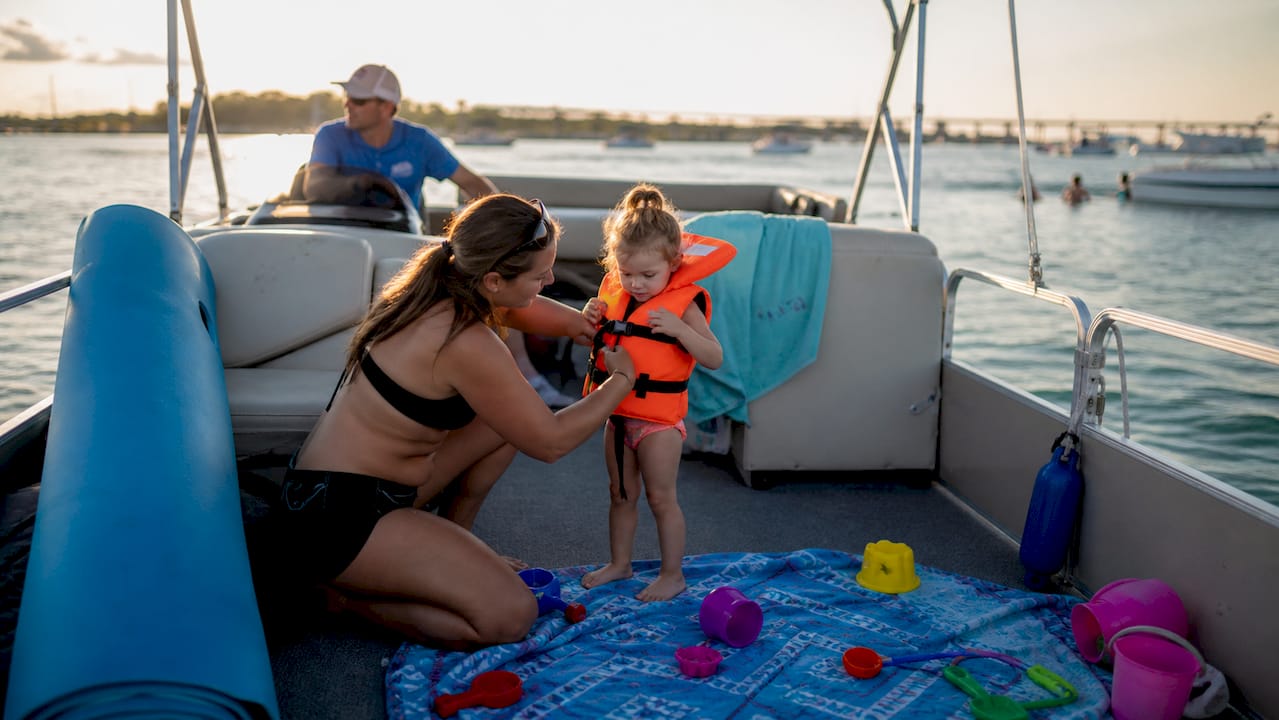 Boat anchored near shallow sandbar, kid with life jacket