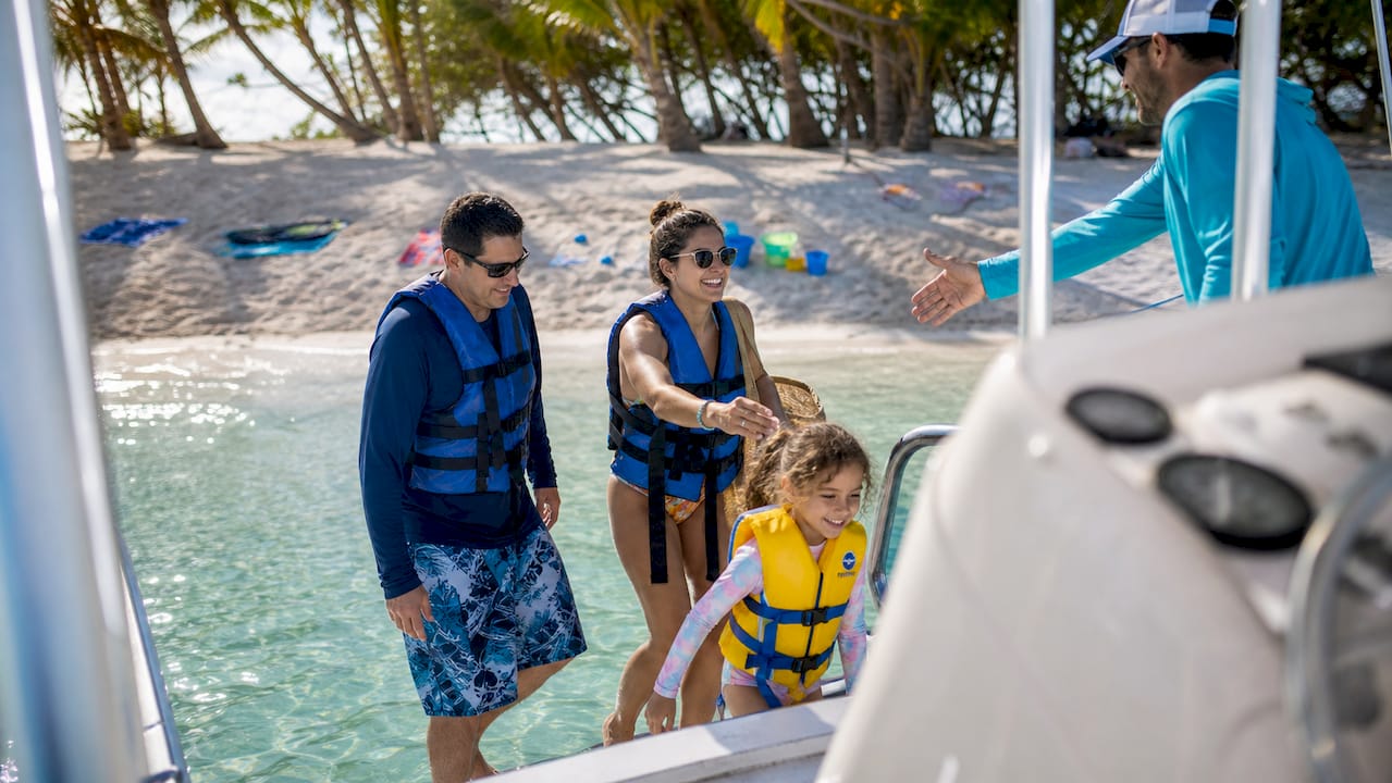 Family boarding captained tour boat at sunny harbor