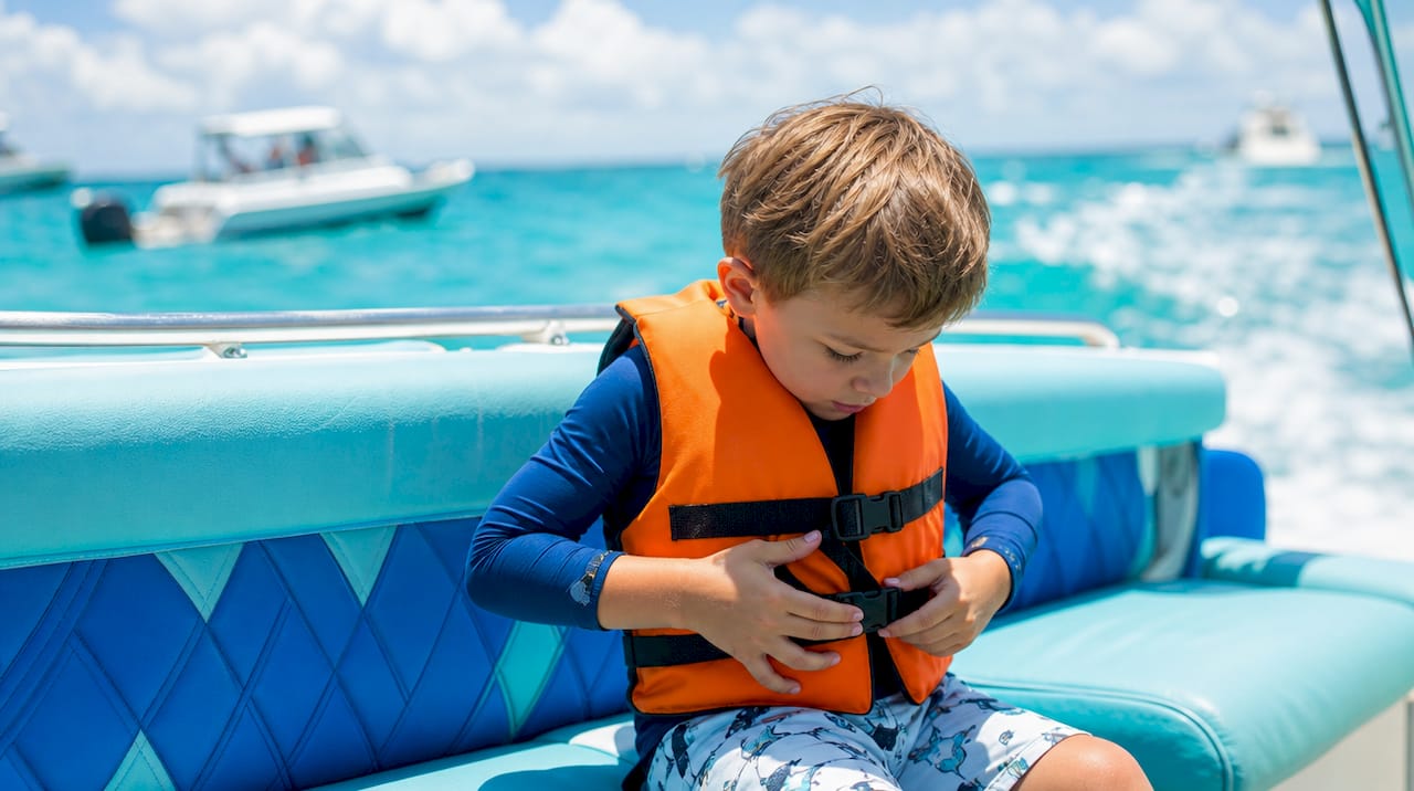 Child fitted with life jacket on boat deck