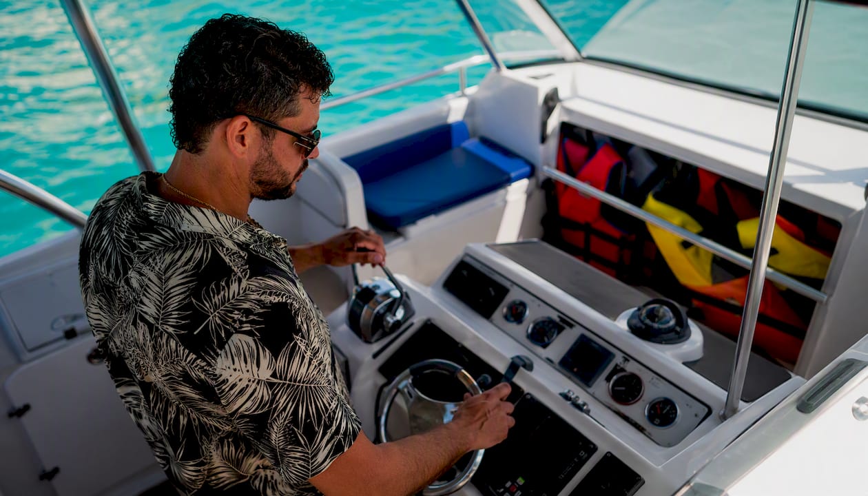 Captain handling boat controls with safety gear visible