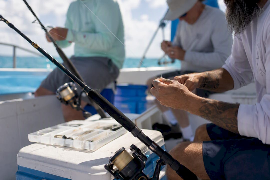 Hands rigging fishing rods on charter boat