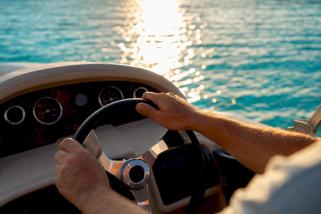 Captain steering pontoon boat on calm water