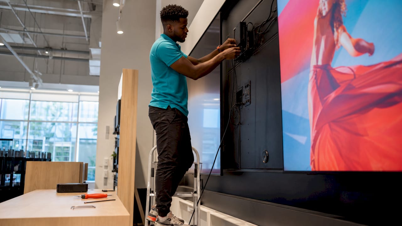 Technician installing media player behind digital display