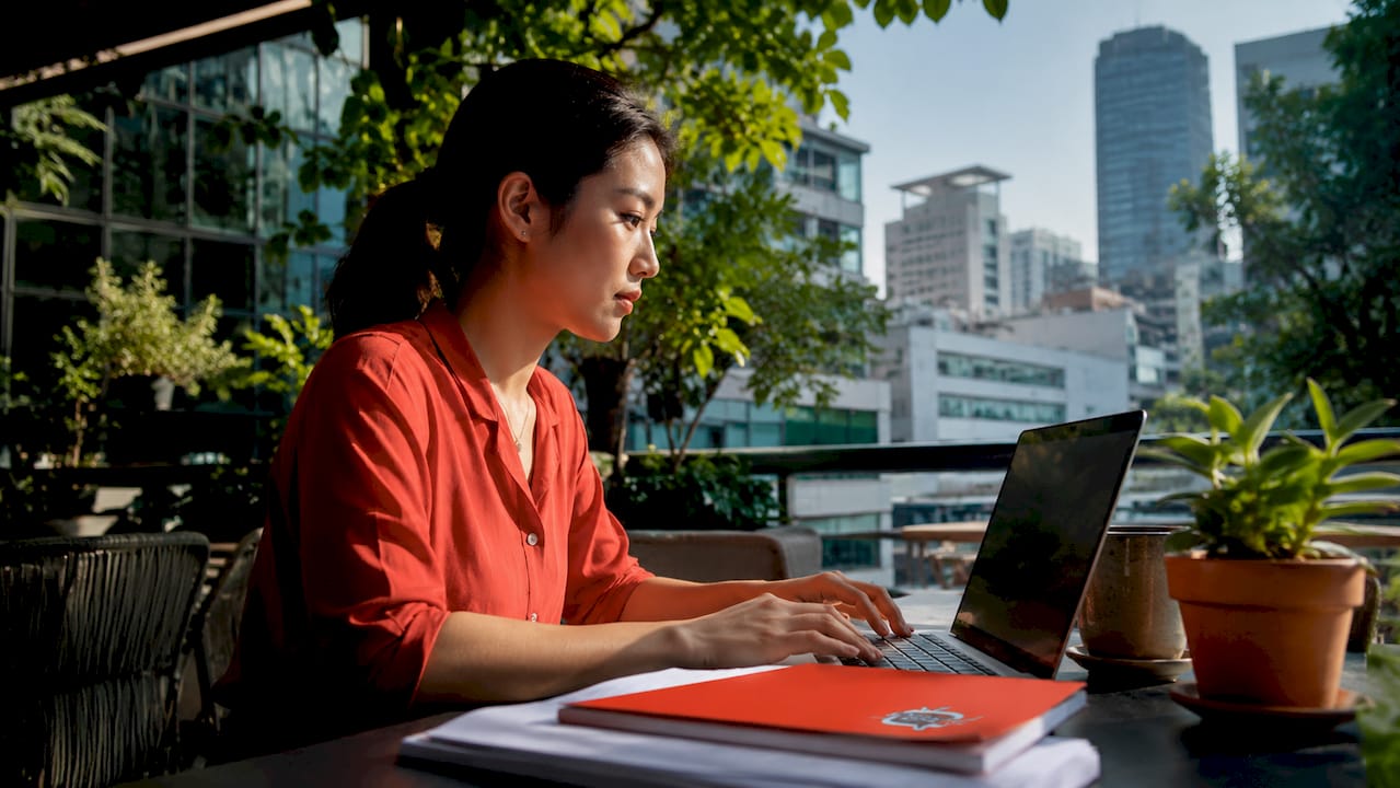 Woman working at desk with physical office screen