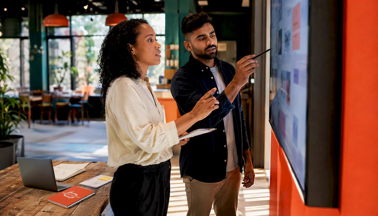 Two colleagues discussing interactive screen content