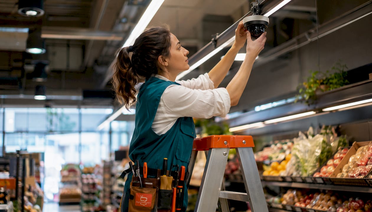 Technician installing AI camera in retail aisle