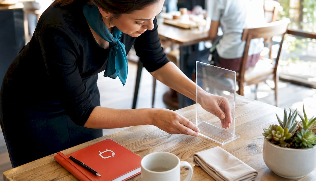 Server placing acrylic tabletop display on restaurant table