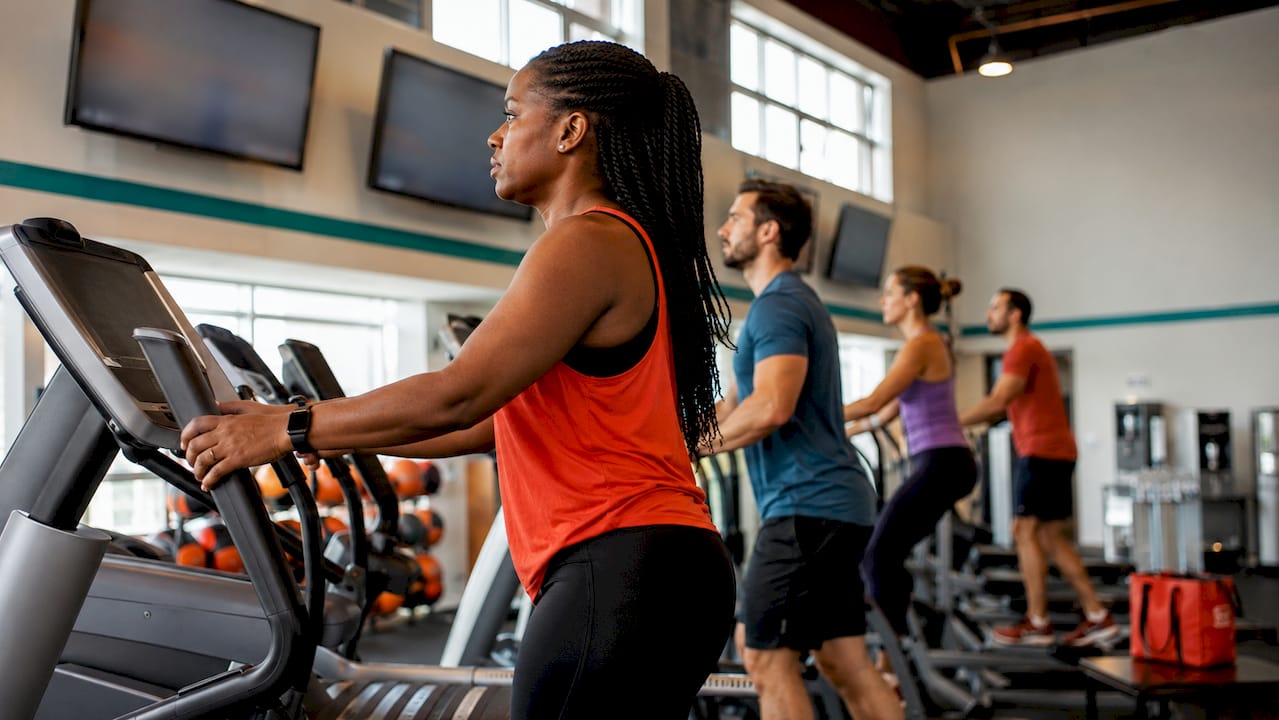 Wide view of gym cardio area with multiple digital screens