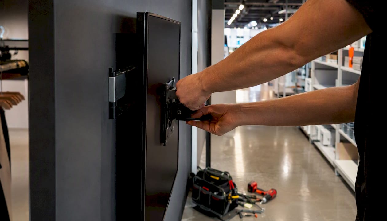 Hands installing digital signage screen