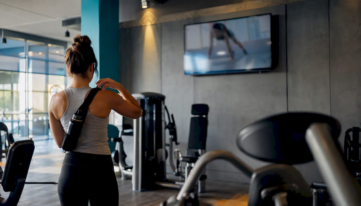 Sports club interior with digital signage and member adjusting towel