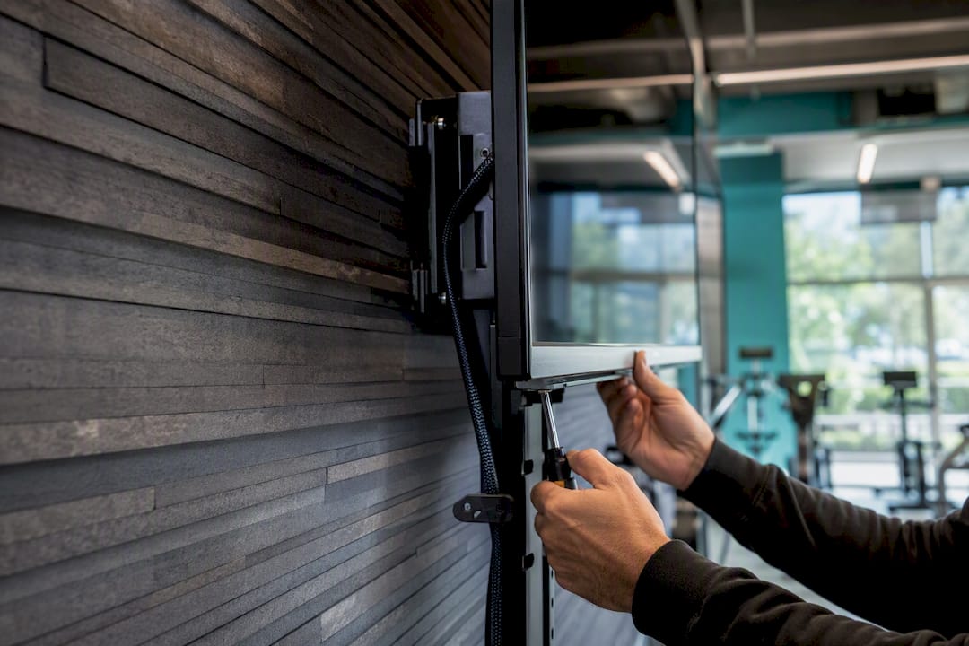 Hands installing digital signage screen mount