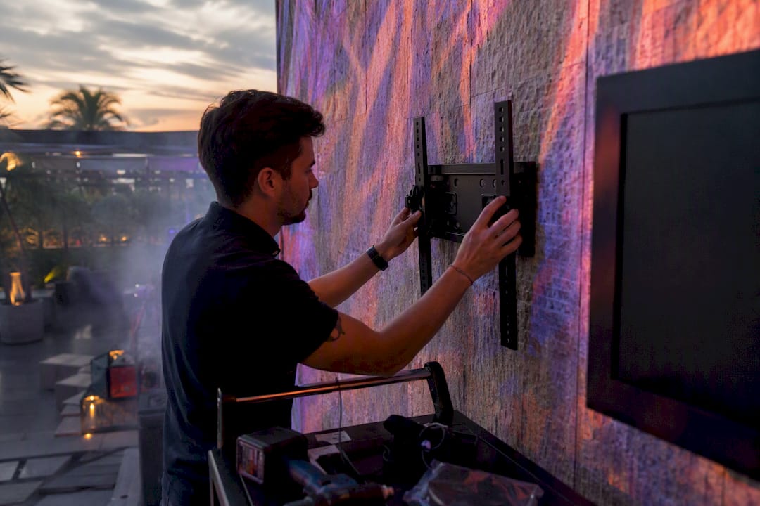 Hands installing digital display bracket in club